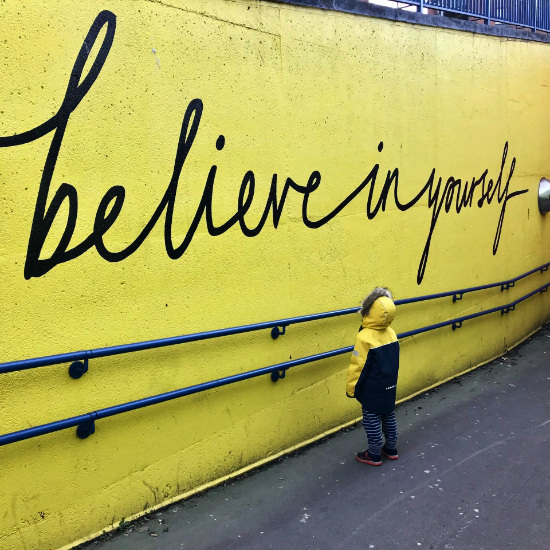 little boy reading graffiti words believe in yourself