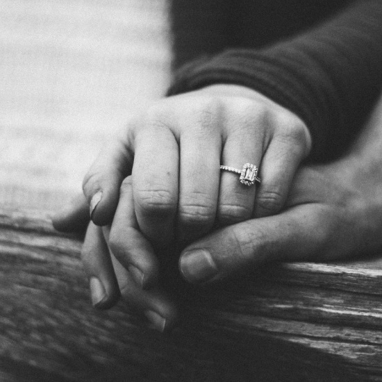 two hands intertwined displaying an engagement ring