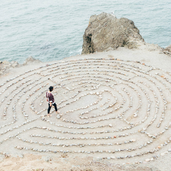 woman walking in a labyrinth of rocks at the coast
